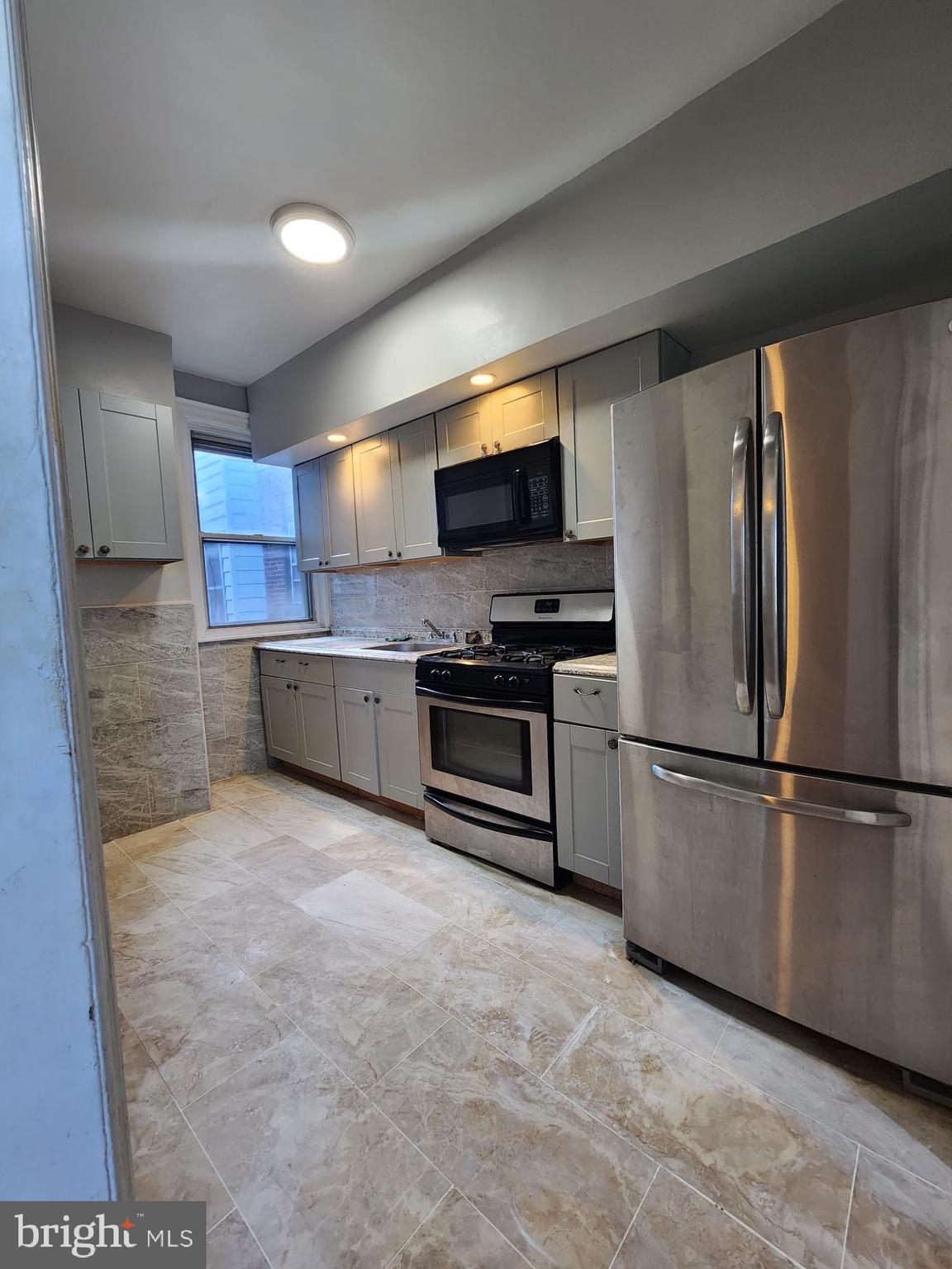 217 South 47th Street, Unit 2 Philadelphia, PA 19139 - Photo 4 of 22 a kitchen with stainless steel appliances a refrigerator and a stove top oven