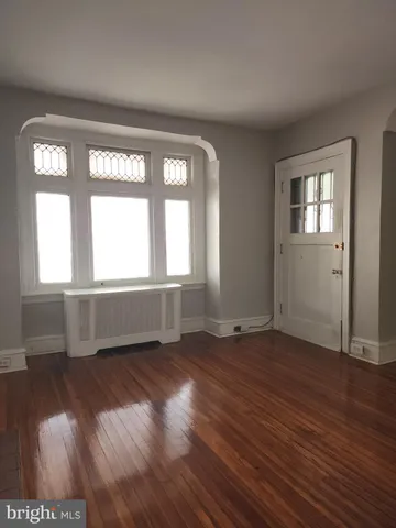an empty room with wooden floor a fireplace and windows