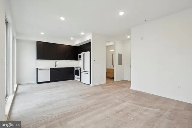 a view of kitchen with stainless steel appliances kitchen island granite countertop a stove a refrigerator and a view of living room