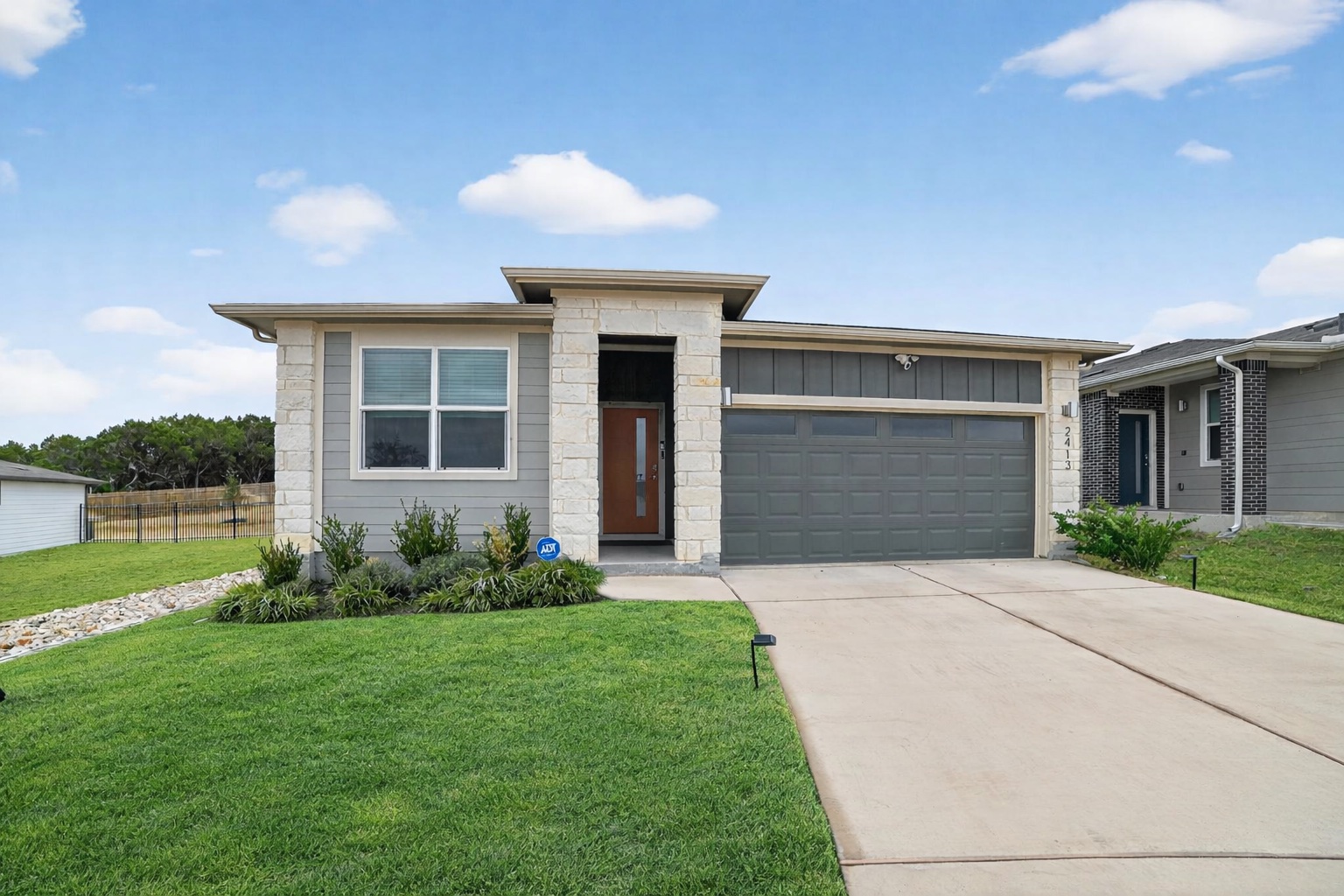 2413 Tucker Lane Austin, TX 78754 - Photo 2 of 26 Prairie-style house featuring concrete driveway, an attached garage, board and batten siding, and stone siding