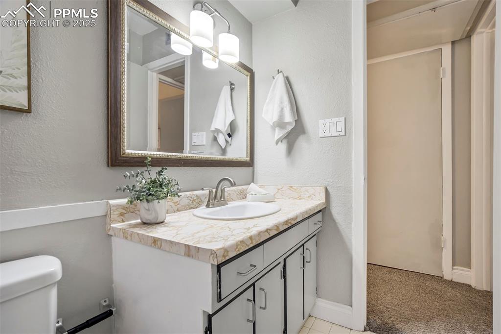 2902 Airport Road, Unit 116 Colorado Springs, CO 80910 - Photo 21 of 32 a bathroom with a granite countertop sink a toilet and a mirror