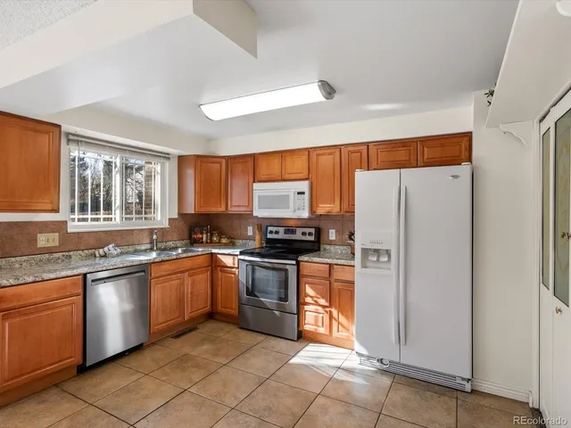 a kitchen with stainless steel appliances granite countertop a refrigerator and a stove top oven