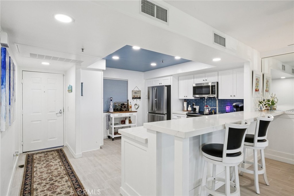 200 Pacific Coast Highway, Unit 130 Huntington Beach, CA 92648 - Photo 7 of 36 a kitchen with stainless steel appliances kitchen island granite countertop a refrigerator and microwave