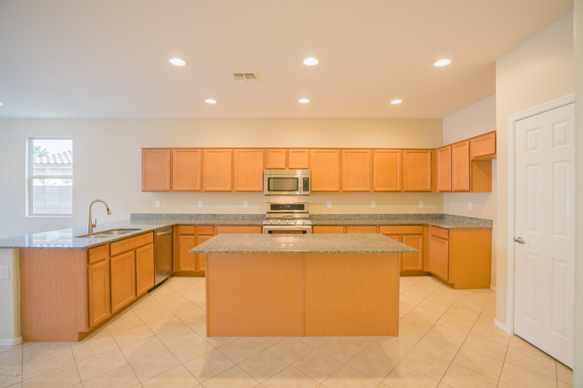 18206 West Hatcher Road Waddell, AZ 85355 - Photo 6 of 27 a large kitchen with a large counter top a sink a window and stainless steel appliances