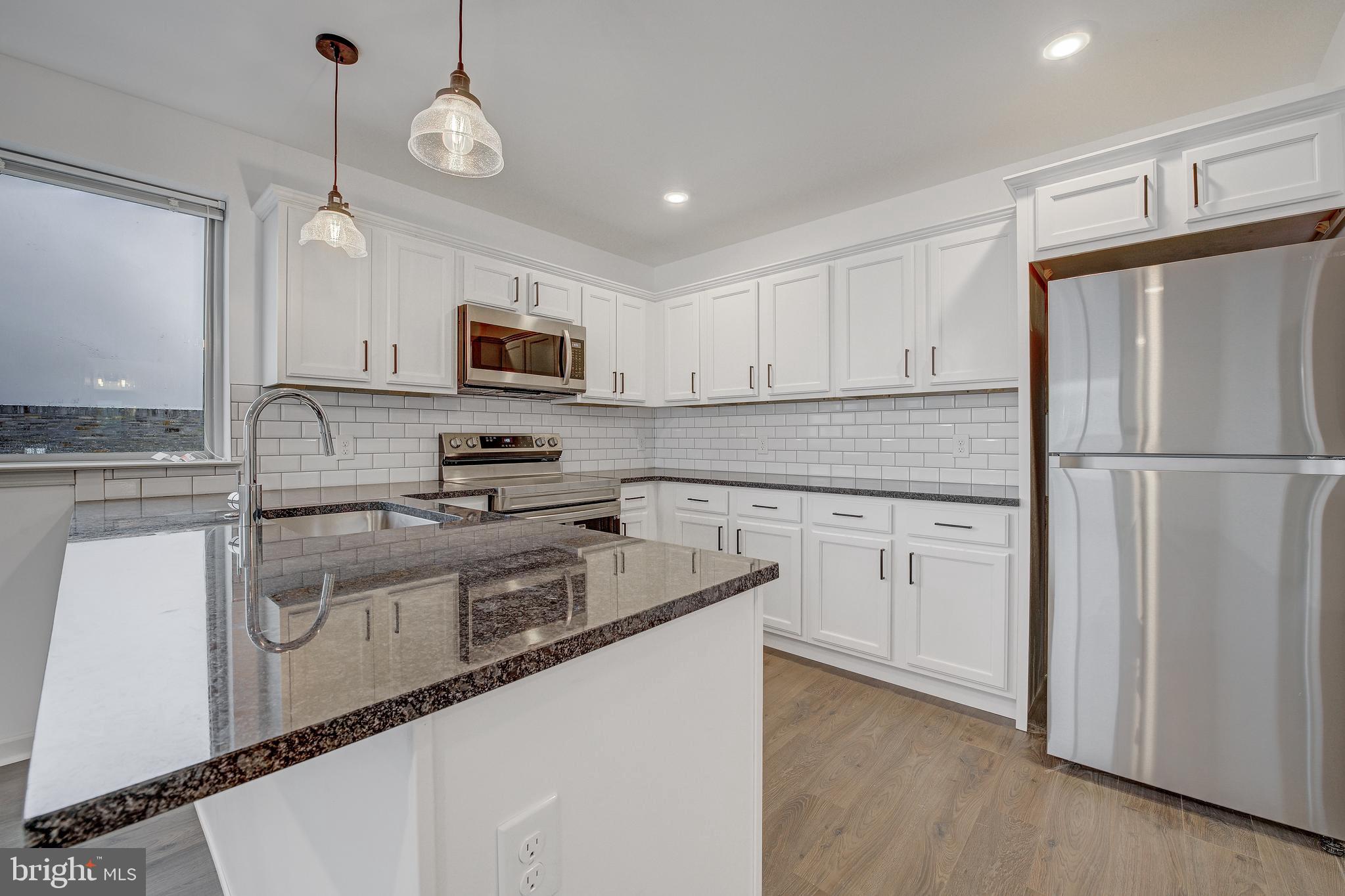 6649 Ridge Avenue, Unit C404 Philadelphia, PA 19128 - Photo 6 of 10 a kitchen with stainless steel appliances granite countertop a refrigerator a stove a sink and a microwave