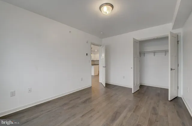 a view of an empty room with wooden floor and closet