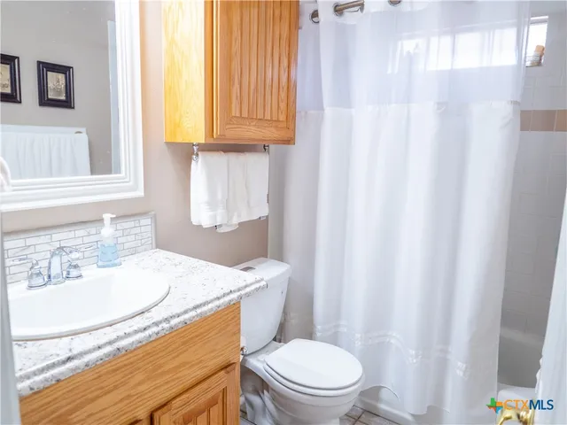a bathroom with a granite countertop sink a mirror and a toilet