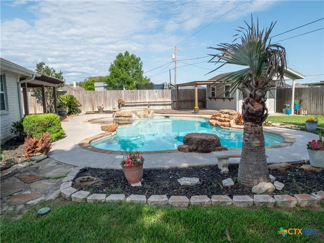 a view of a backyard with table and chairs potted plants and large tree