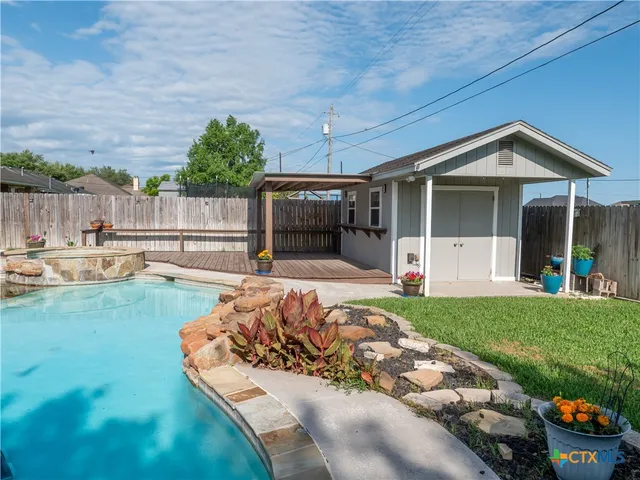 a view of swimming pool with outdoor seating and house in the background