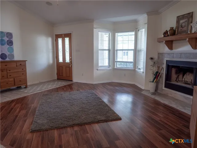 a view of an empty room with wooden floor fireplace and a window