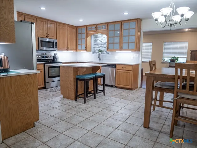 a kitchen with kitchen island granite countertop a sink cabinets and stainless steel appliances