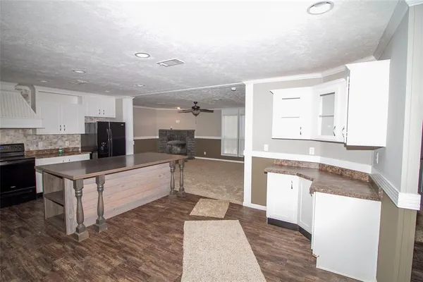 a large white kitchen with kitchen island sink and refrigerator