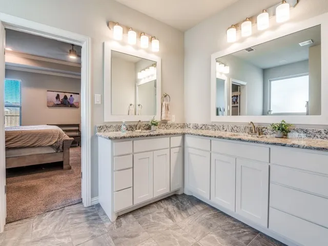 a en suite bathroom with a granite countertop sink and a mirror
