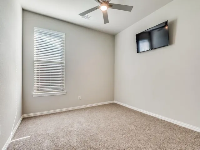 an empty room with a ceiling fan and a window