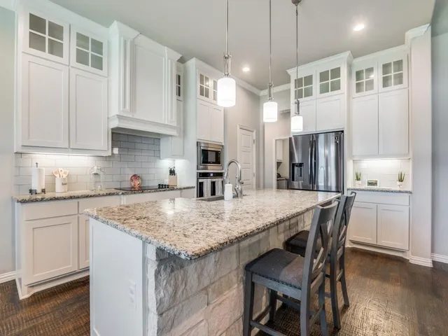 a kitchen with stainless steel appliances granite countertop a kitchen island a stove a refrigerator a sink a dining table and chairs