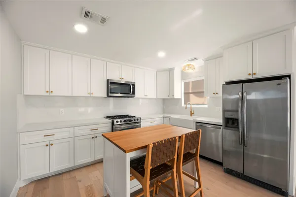 a kitchen with stainless steel appliances a refrigerator a sink a stove a table and chairs