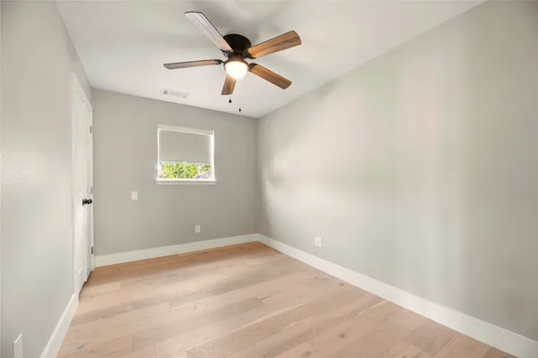 an empty room with a window and a fan