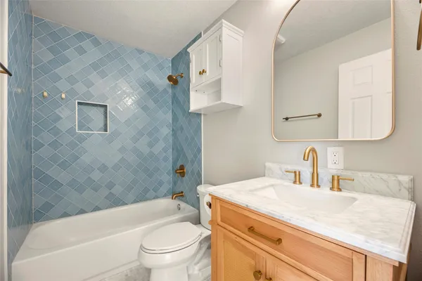 a bathroom with a granite countertop sink a toilet and bathtub