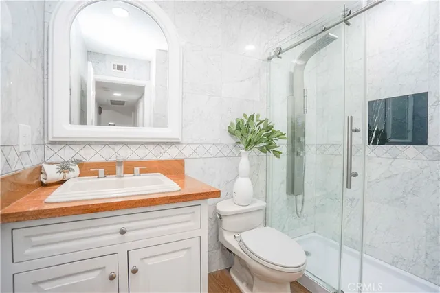 a kitchen with a stove a sink and white cabinets with wooden floors