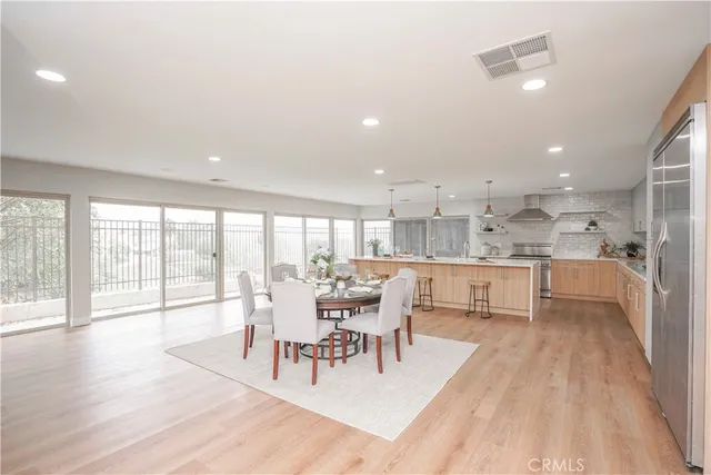 a large white kitchen with stainless steel appliances kitchen island a stove a sink dishwasher and a refrigerator with wooden floor