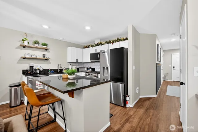 a kitchen with stainless steel appliances a refrigerator a stove a sink and a dining table with wooden floor