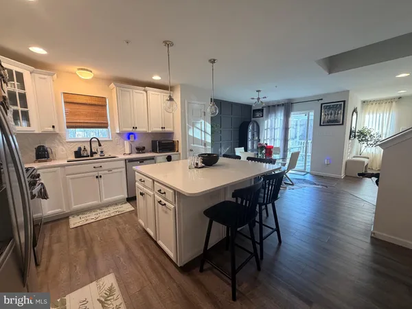 a kitchen with a sink a center island a wooden floor and a view of living room