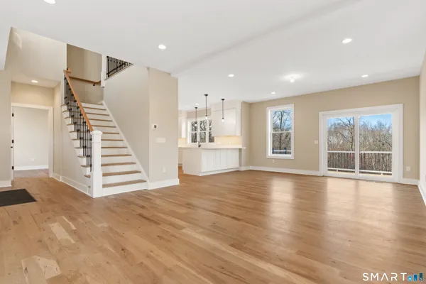 a view of an empty room with wooden floor and windows