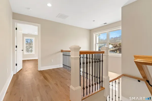 a view of a hallway with wooden floor and windows