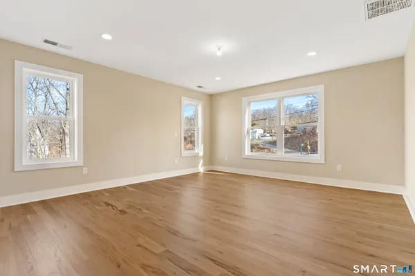a view of an empty room with window and wooden floor