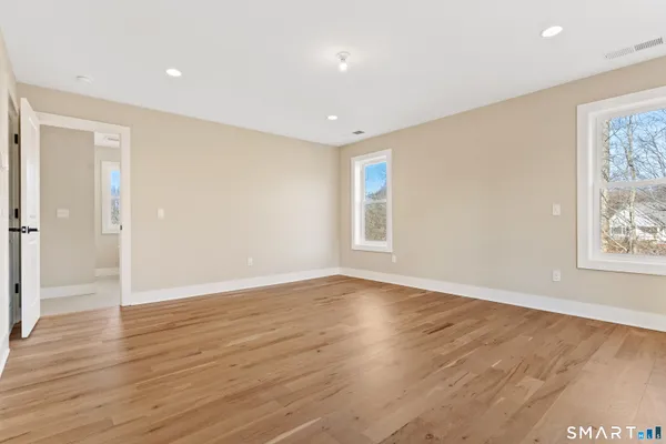 an empty room with wooden floor and windows