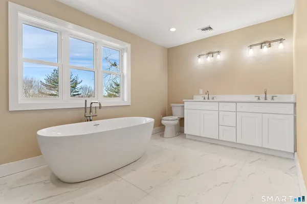 a spacious bathroom with a tub sink and mirror