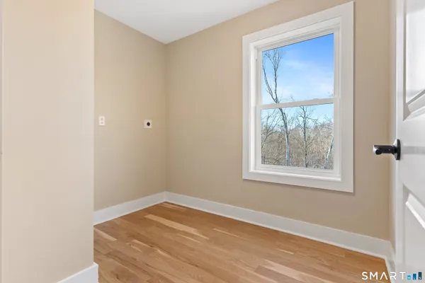 a view of an empty room with wooden floor and a window