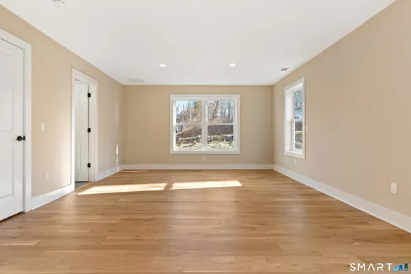 a view of an empty room with wooden floor and a window