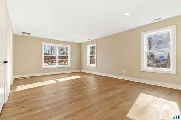 an empty room with wooden floor and windows
