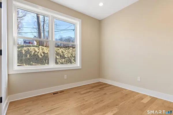 a view of empty room with wooden floor and fan