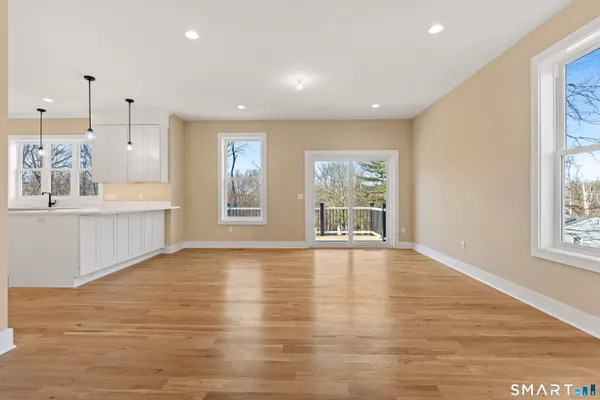 a view of an empty room with a window and wooden floor
