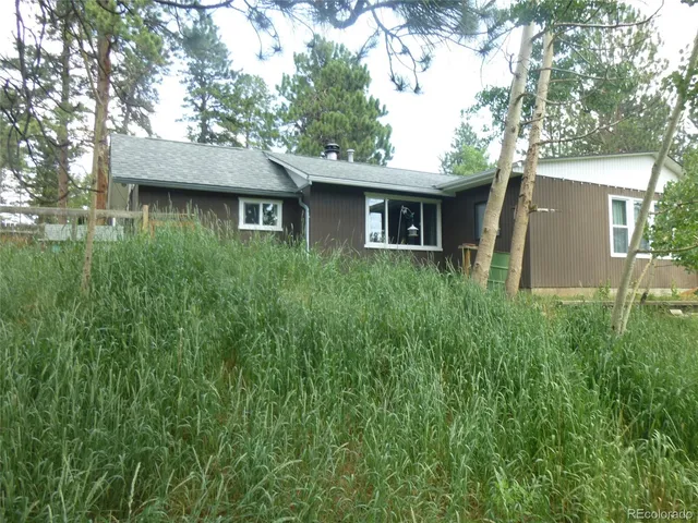 a view of a backyard with couches table and chairs with wooden fence