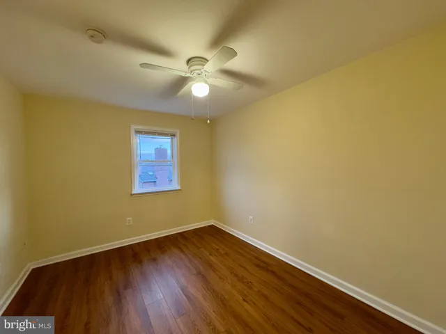 a view of a room with wooden floor and a ceiling fan