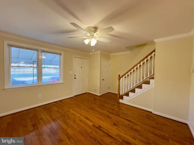 a view of an empty room with a window and wooden floor