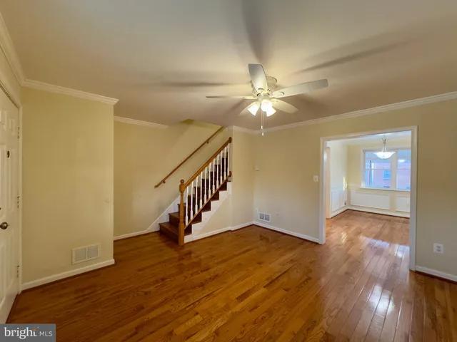 wooden floor in an empty room with a chandelier fan