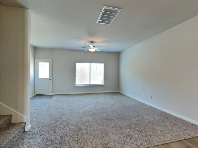 an empty room with chandelier fan and windows