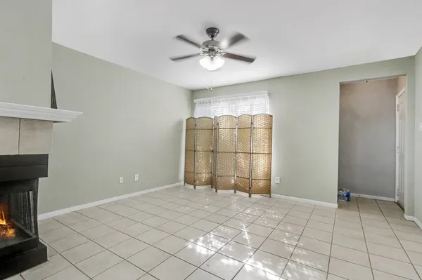 a view of an empty room with window and chandelier fan