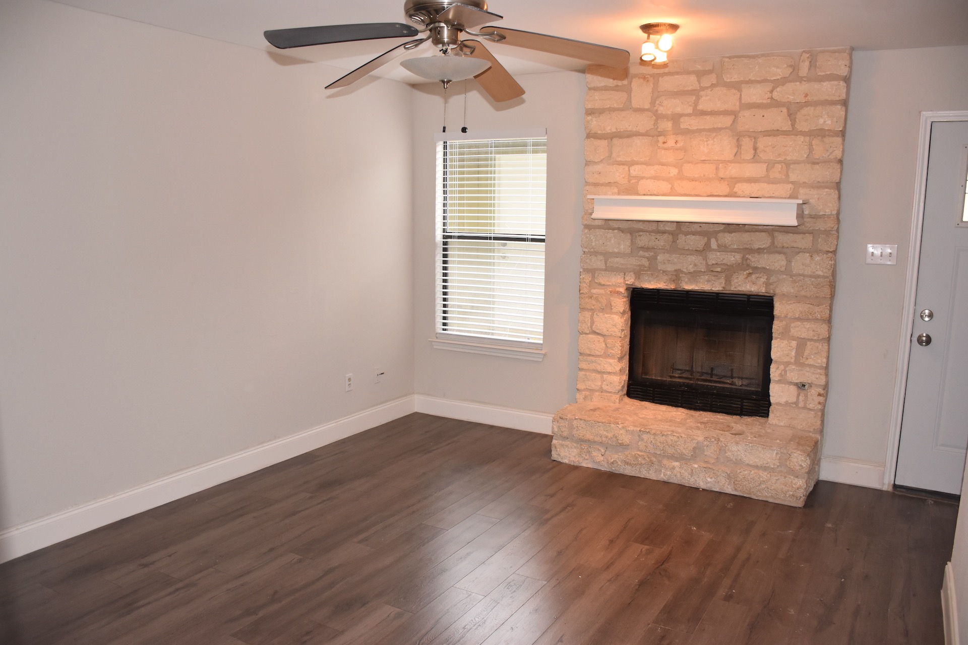1810 Rawhide Loop Round Rock, TX 78681 - Photo 8 of 29 Stone fireplace with a white mantel, wood-finish flooring, and neutral wall tones