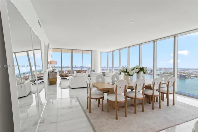 a room with lots of tables a large window and chairs