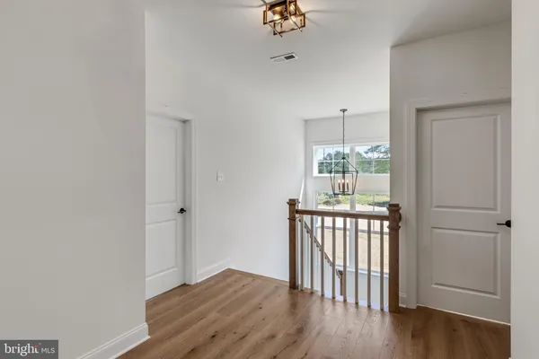 a view of a hallway with wooden floor and chandelier