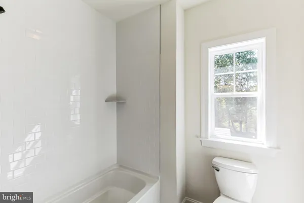 a bath room with a toilet a bath tub and a window