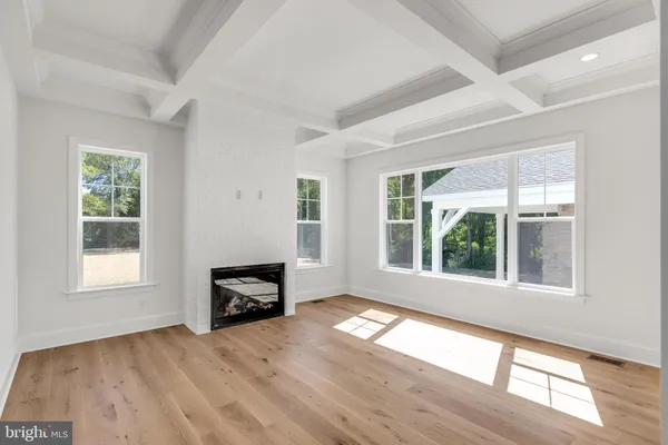 an empty room with windows fireplace and wooden floor