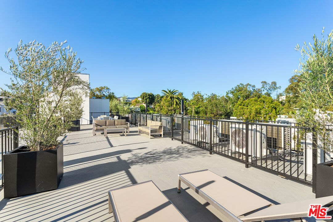 11620 Chenault Street, Unit 103 Los Angeles, CA 90049 - Photo 19 of 21 a view of a patio with couches and table and chairs with wooden floor and fence