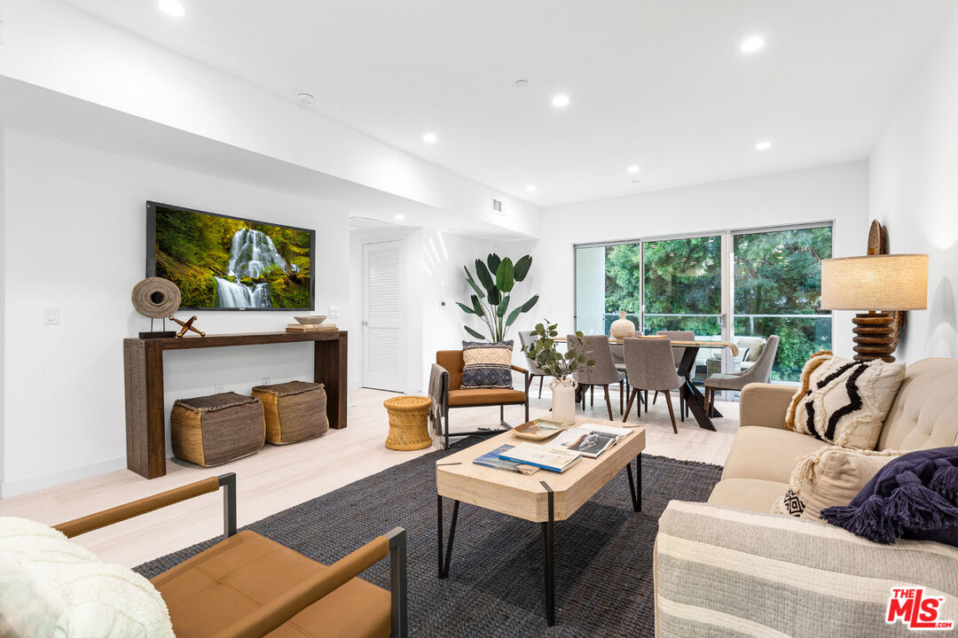 11620 Chenault Street, Unit 103 Los Angeles, CA 90049 - Photo 4 of 21 a living room with furniture a fireplace and a floor to ceiling window
