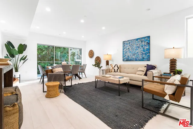a living room with furniture kitchen view and a large window